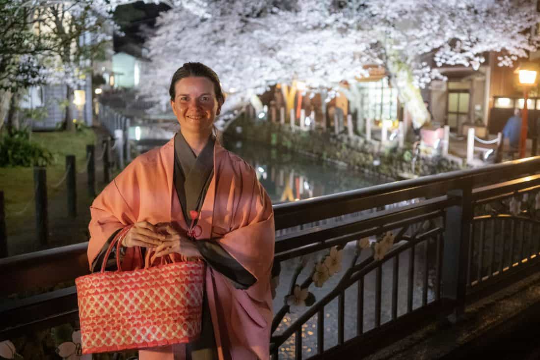 Erin in kimono by the cherry blossom lined canal in Kinosaki Onsen