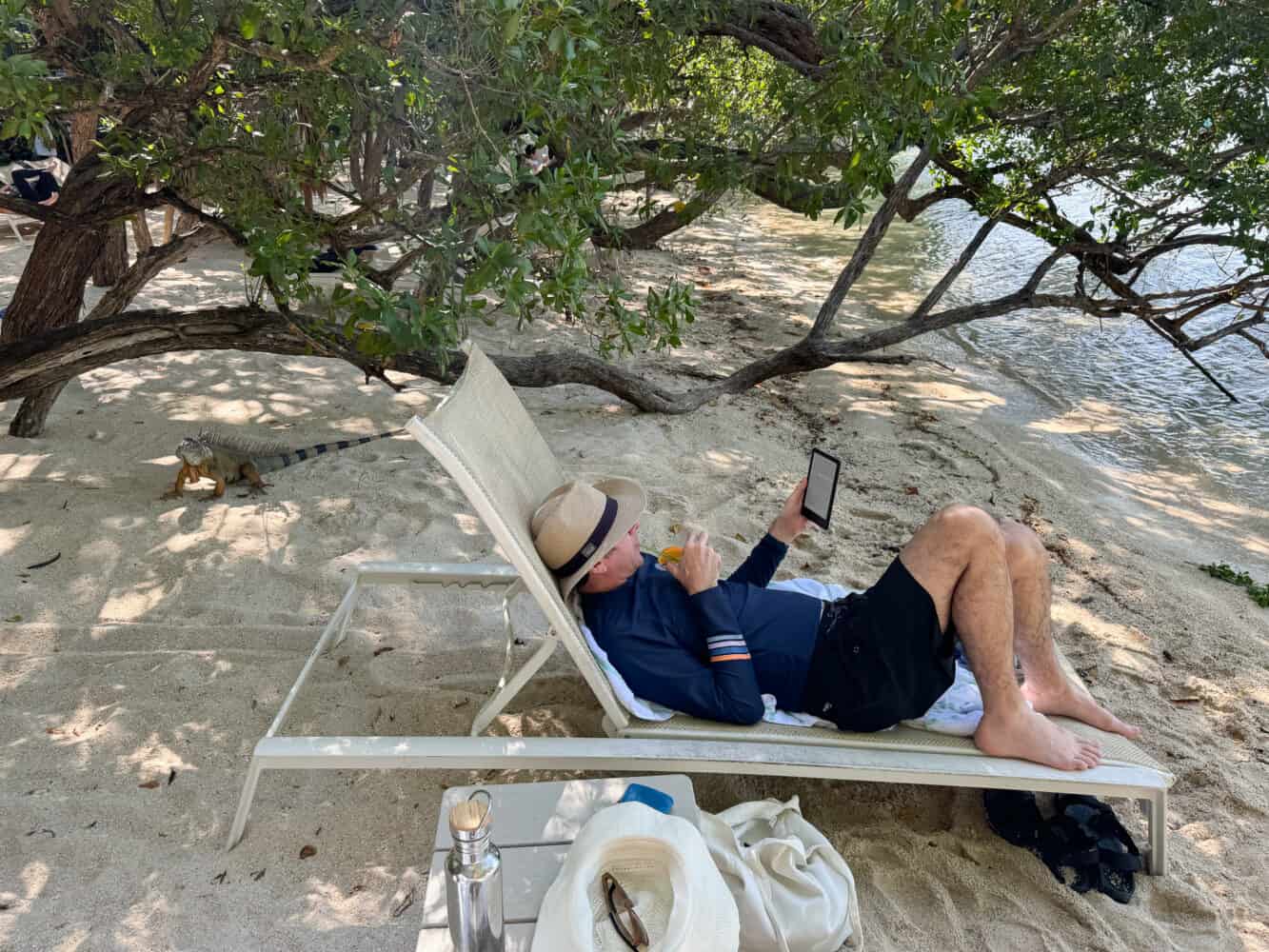 Simon chilling on Hammock Beach at Baker's Cay Resort with an iguana behind