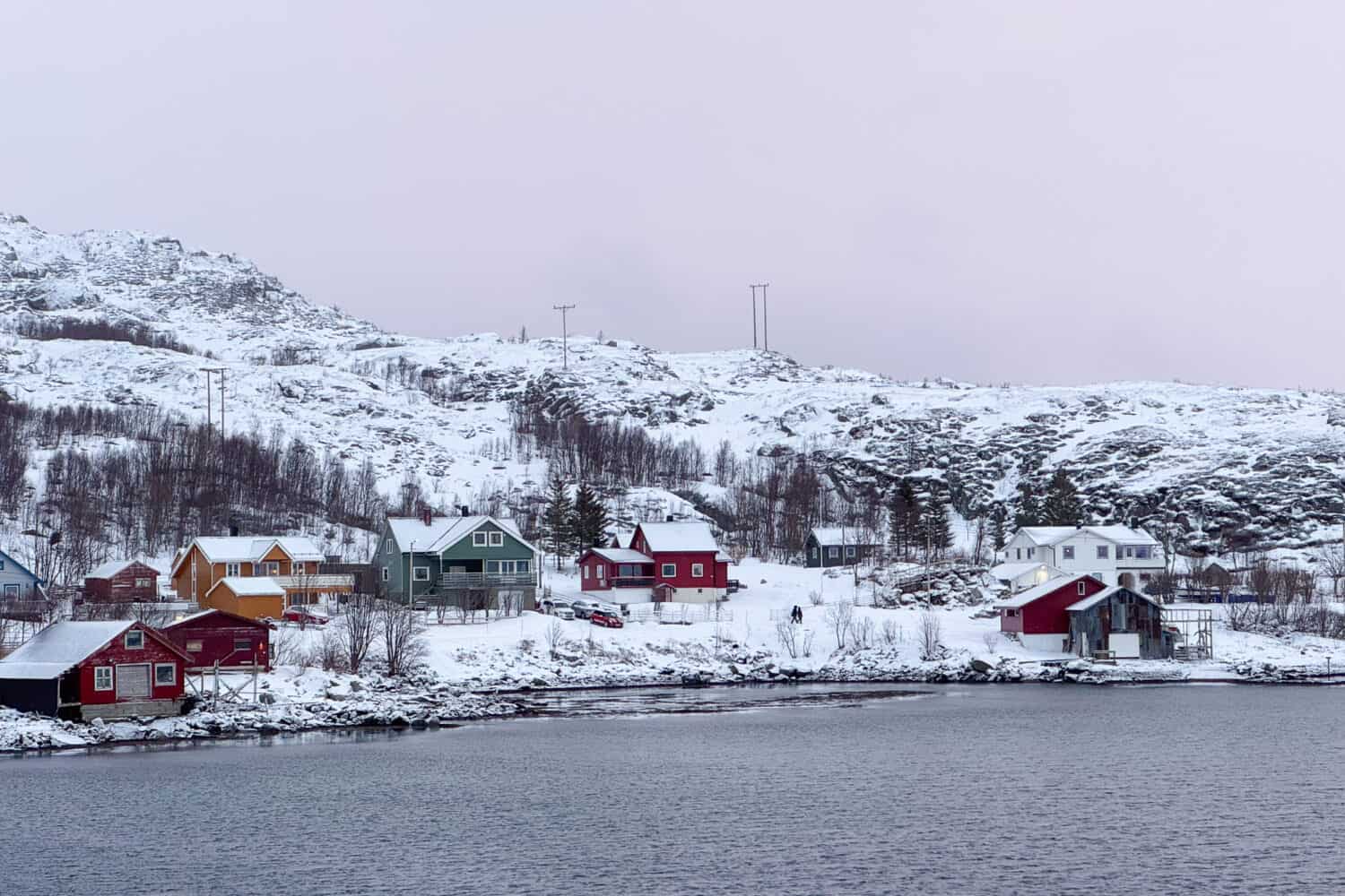 View of snowy mountains, huts and fjord in Ersfjordbotn, Kvaloya, Norway