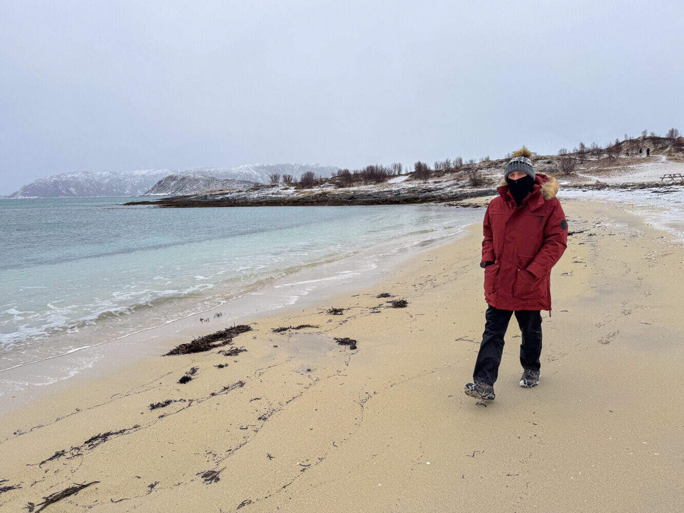 Simon walking along Steinsvika beach in winter, Sommaroy, Norway